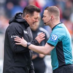 96-Trainer Christian Titz (l) spricht mit Schiedsrichter Robert Kampka. Foto: David Inderlied/dpa