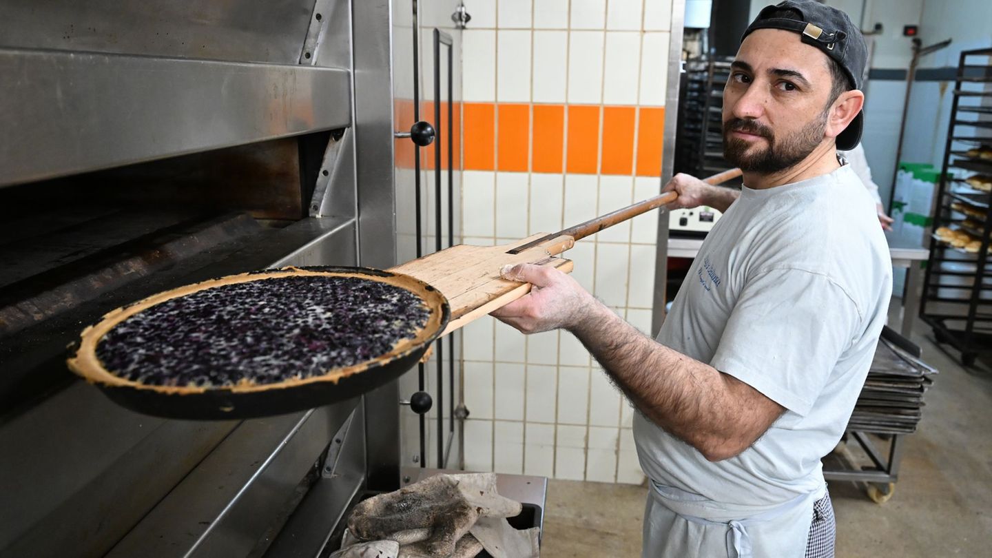 Bäcker Sulaiman Shapal nimmt ein Blech mit Blaubeerkuchen aus einem Ofen in einer Backstube. Er ist aus Syrien nach Deutschland