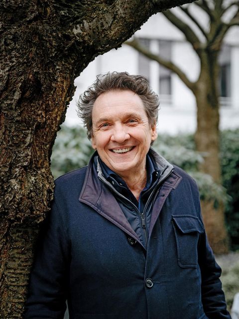 Erhard Dietl lehnt lachend an einem Baum