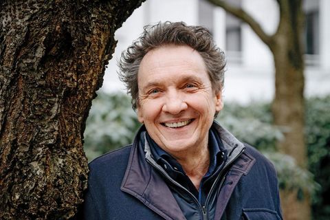 Erhard Dietl lehnt lachend an einem Baum