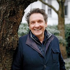 Erhard Dietl lehnt lachend an einem Baum