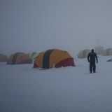 Muschelzelte auf dem Eis der Antarktis, dazwischen Menschen und Nebel