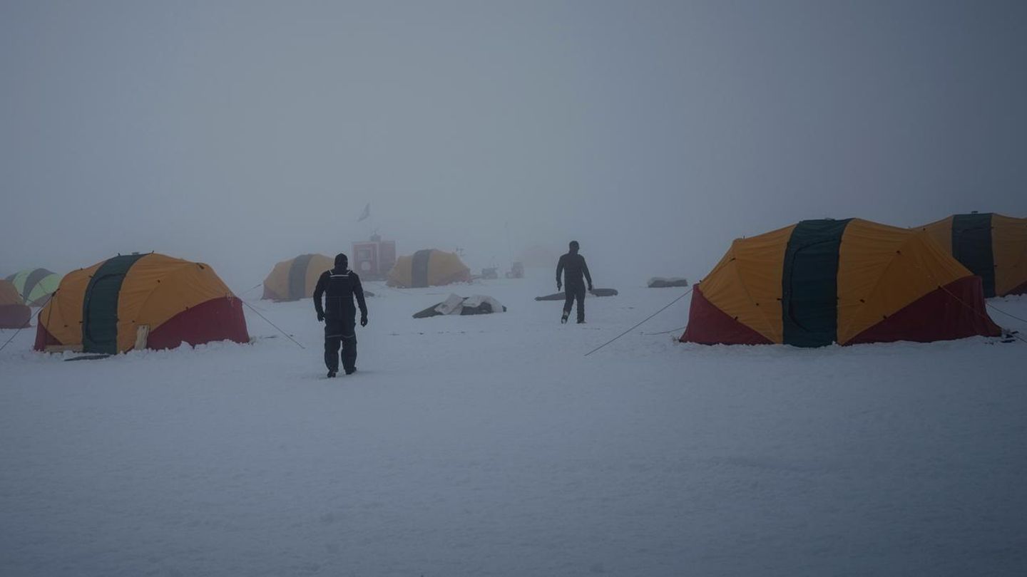 Muschelzelte auf dem Eis der Antarktis, dazwischen Menschen und Nebel