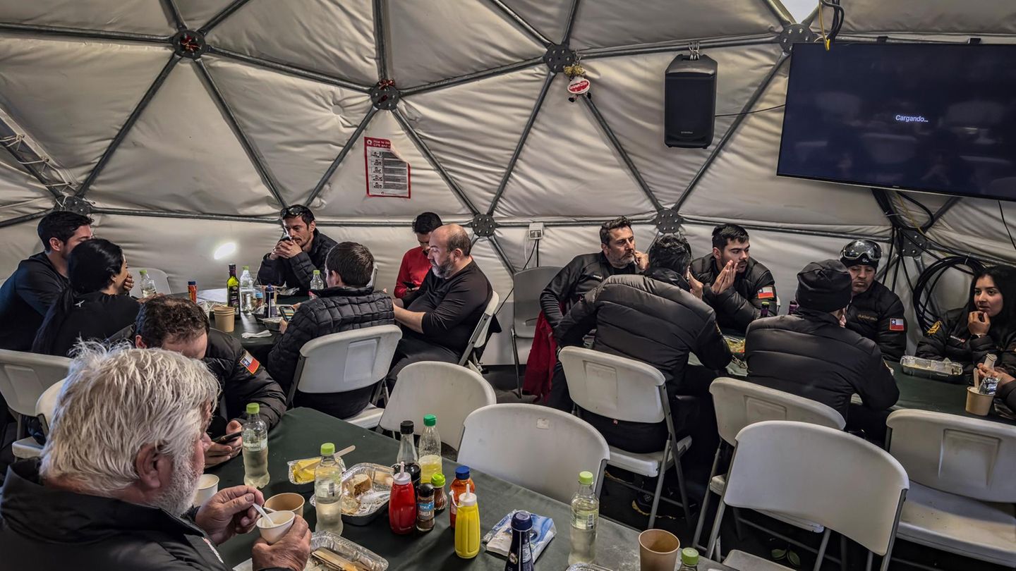 Unter dem Eis der Antarktis sitzen Forscherinnen und Forscher im Kantinenzelt ihrer Station zusammen