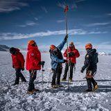 In der Antarktis markiert Forscher Jaña Messpunkte mit Bambusstäben, drumherum stehen mehrere Menschen