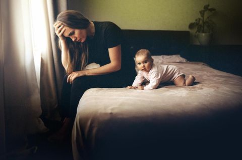 Traurige Frau mit Baby auf Bett