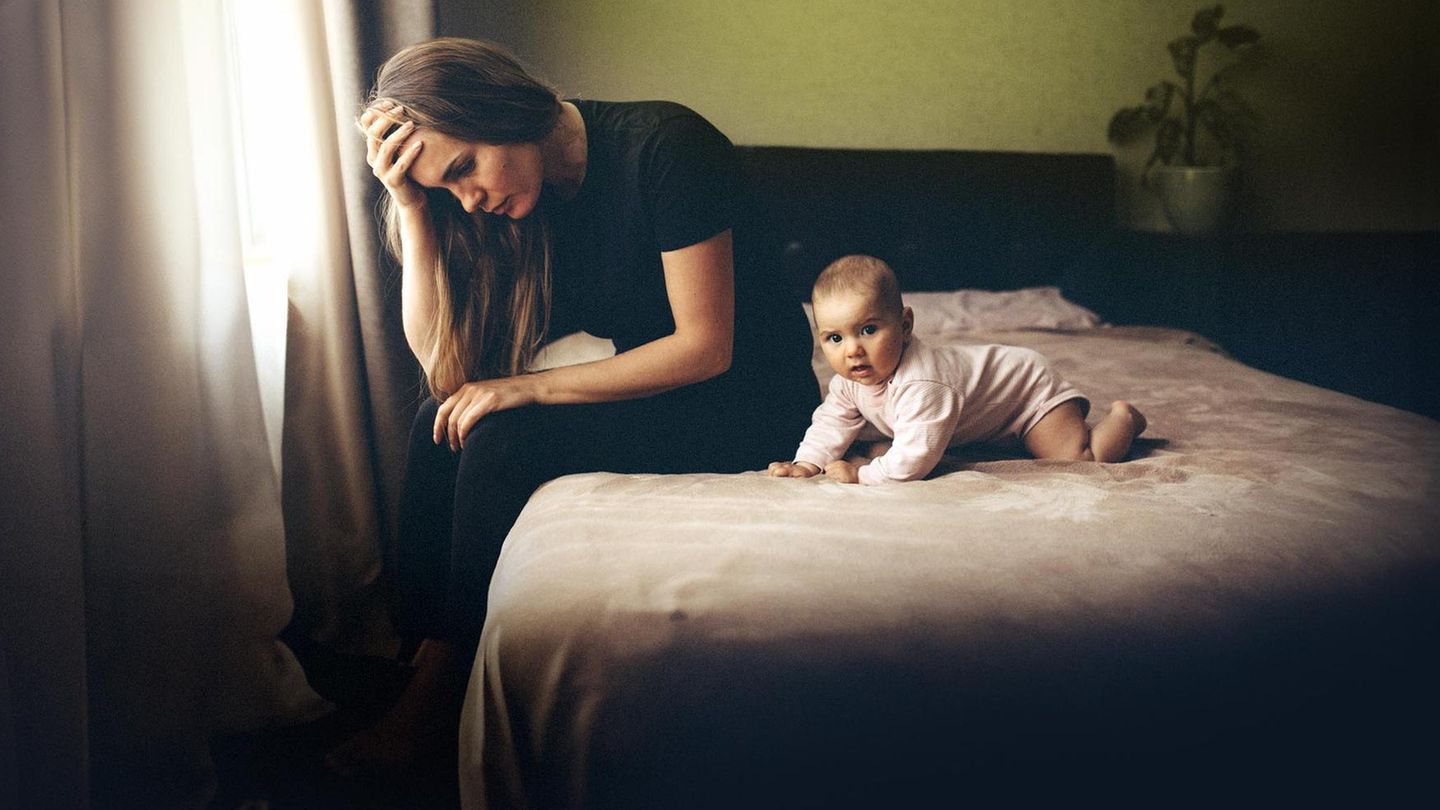 Traurige Frau mit Baby auf Bett