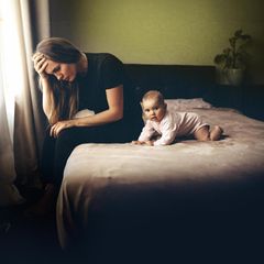 Traurige Frau mit Baby auf Bett