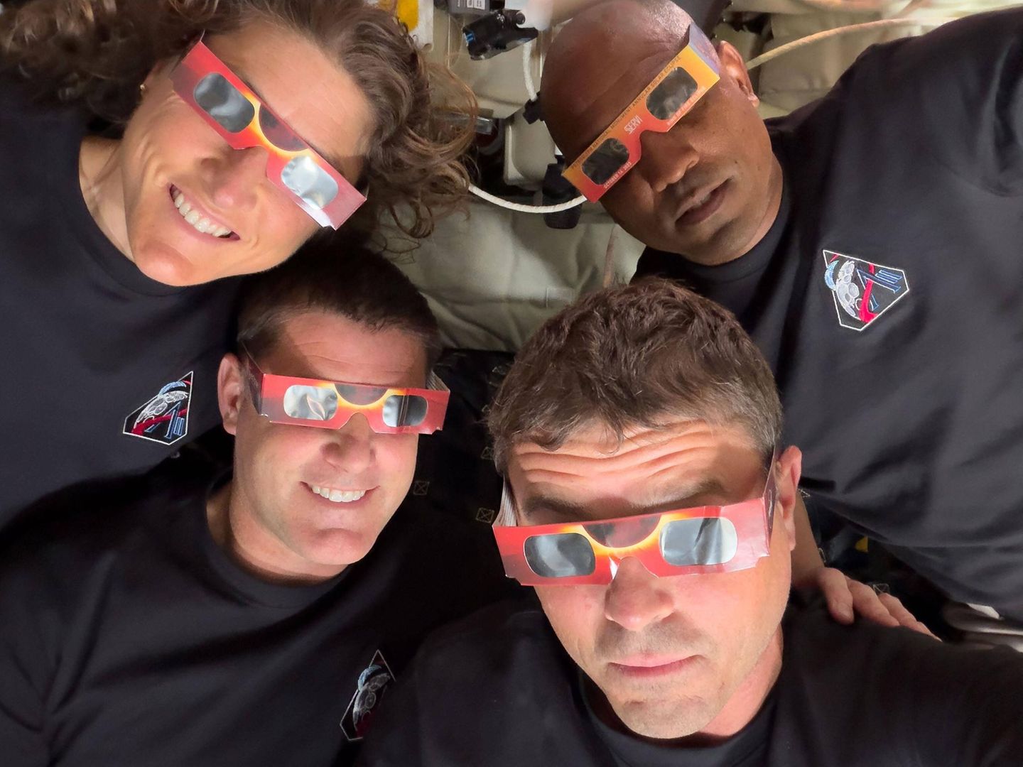 Orion-Raumkapsel, Weltraum. Die Astronauten haben sich Schutzbrillen aufgesetzt, weil sie auf dem Weg rund um den Mond eine Sonnenfinsternis erlebten. Mittlerweile befinden sich die vier Astronauten Christina Koch (v.l.n.r.), Jeremy Hansen, Reid Wiseman und Victor Glover auf dem Rückflug zur Erde.