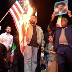 Iranische Regime-Anhänger feiern auf den Straßen und zünden eine USA-Flagge an.
