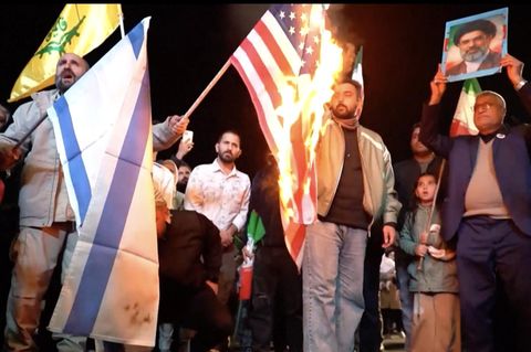 Iranische Regime-Anhänger feiern auf den Straßen und zünden eine USA-Flagge an.