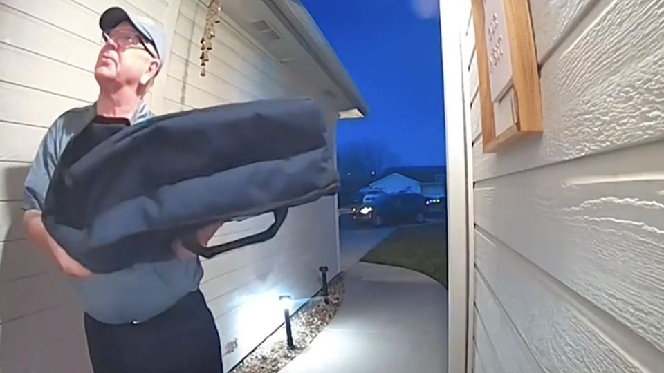 Ein Pizzalieferant steht vor einem Haus.