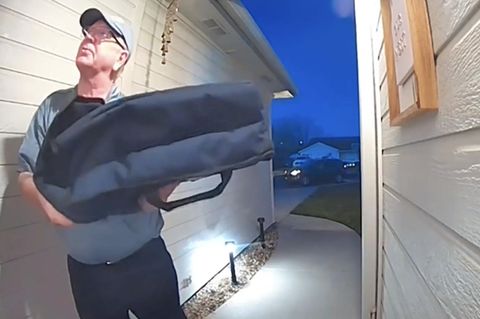 Ein Pizzalieferant steht vor einem Haus.