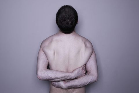 Ein nackter, männlicher Oberkörper eines Narzissten umarmt sich selbst