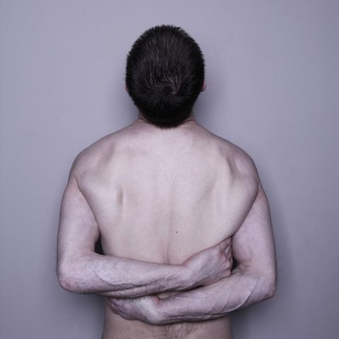 Ein nackter, männlicher Oberkörper eines Narzissten umarmt sich selbst