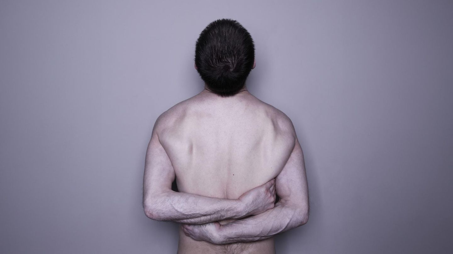 Ein nackter, männlicher Oberkörper eines Narzissten umarmt sich selbst