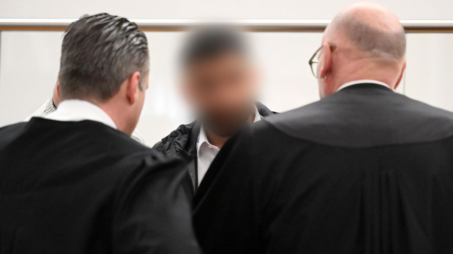 Der Angeklagte (M) spricht im Gerichtssaal mit zwei Strafverteidigern. Zu Prozessbeginn sind weiterhin viele Fragen offen. Foto: