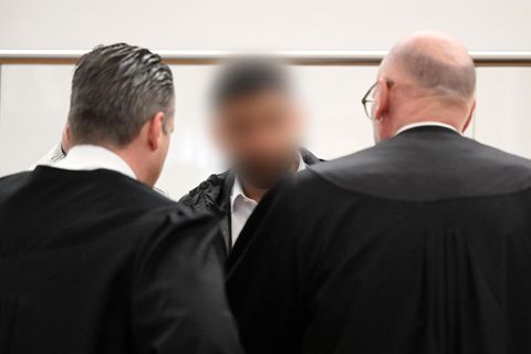 Der Angeklagte (M) spricht im Gerichtssaal mit zwei Strafverteidigern. Zu Prozessbeginn sind weiterhin viele Fragen offen. Foto: