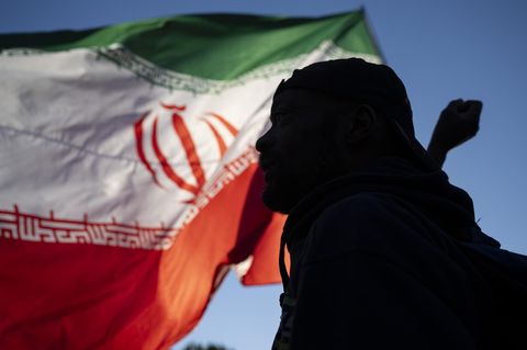 Der Schatten eines Mannes vor der iranischen Flagge