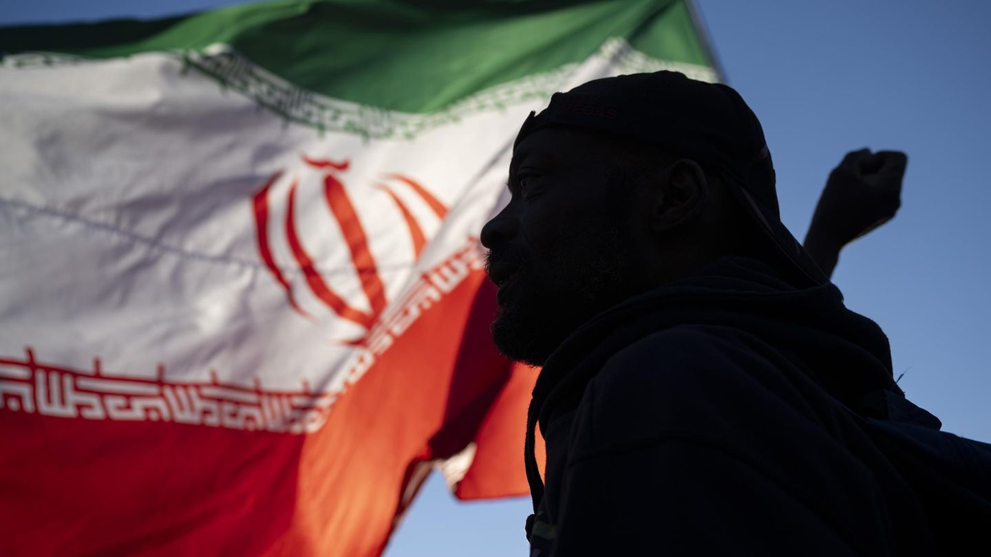 Der Schatten eines Mannes vor der iranischen Flagge