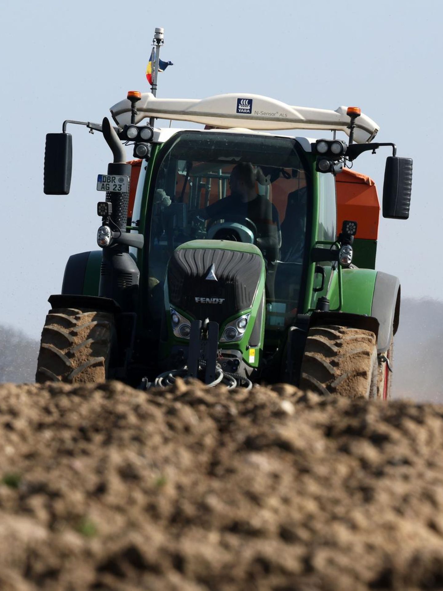 Ein Landwirt fährt in einem grünen Traktor über einen leeren Acker