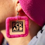 Eine Frau trägt einen pinkfarbigen Ohrring mit einem Anti-AFD Schriftzug