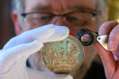 Ulf Dräger, Leiter des Landesmünzkabinetts Sachsen-Anhalt, begutachtet eine Silber-Medaille von 1629. Foto: Hendrik Schmidt/dpa