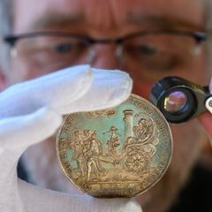 Ulf Dräger, Leiter des Landesmünzkabinetts Sachsen-Anhalt, begutachtet eine Silber-Medaille von 1629. Foto: Hendrik Schmidt/dpa