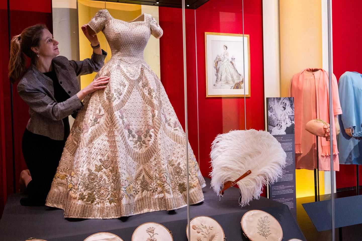 … in diesem Kleid, das ihr ebenfalls von Norman Hartnell auf den Leib geschneidert wurde. Elizabeth wünschte farbige Stickereien darauf, damit es sich von ihrem Hochzeitskleid unterschied. Es war mit Symbolen der Länder des Commonwealth verziert, einem walisischen Lauch etwa, einer schottischen Distel oder einem kanadischen Ahornblatt.