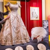 … in diesem Kleid, das ihr ebenfalls von Norman Hartnell auf den Leib geschneidert wurde. Elizabeth wünschte farbige Stickereien darauf, damit es sich von ihrem Hochzeitskleid unterschied. Es war mit Symbolen der Länder des Commonwealth verziert, einem walisischen Lauch etwa, einer schottischen Distel oder einem kanadischen Ahornblatt.