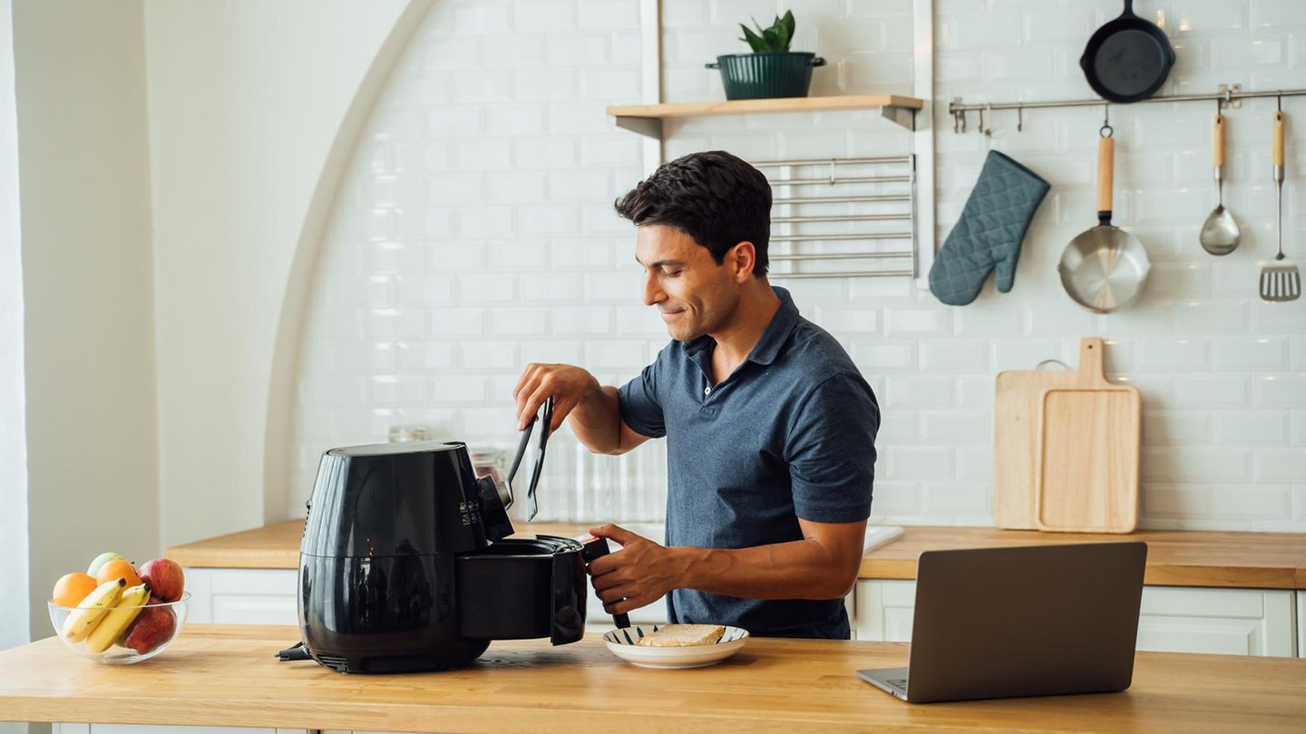 Ein Mann bedient eine Tefal Heißluftfritteuse.