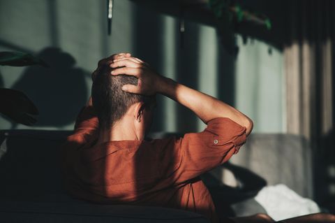 Mann von hinten. Er fasst sind mit den Händen an den Kopf. Kaufsucht kann hohe Schulden verursachen.