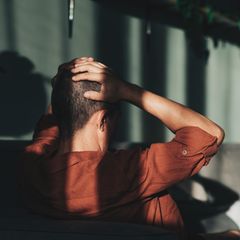 Mann von hinten. Er fasst sind mit den Händen an den Kopf. Kaufsucht kann hohe Schulden verursachen.