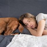 Eine Frau liegt mit ihrem Hund auf dem Sofa