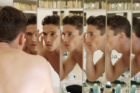 Symbolbild Looksmaxxing: Ein Mann betrachtet sich kritisch im Spiegel