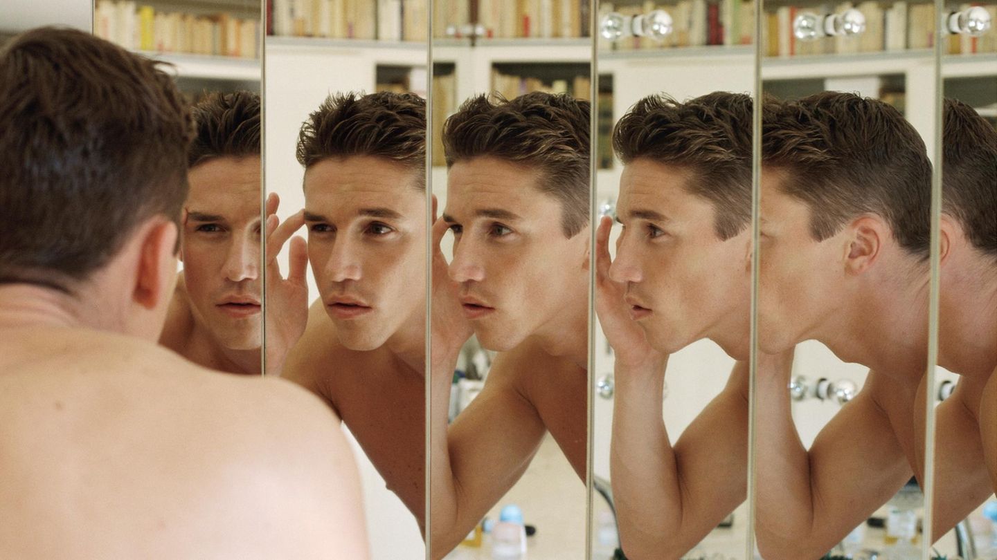 Symbolbild Looksmaxxing: Ein Mann betrachtet sich kritisch im Spiegel