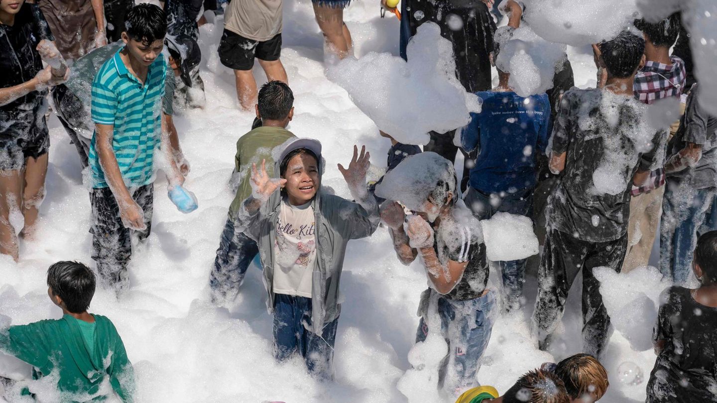 Yangon, Myanmar. Bei den Feierlichkeiten zum buddhistischen Neujahrs-Wasserfest in Myanmar, auch bekannt als Thingyan, spielen Kinder mit Seifenblasen in Bergen von Schaum. Immerhin kommen sie nicht schmutzig vom Spielen nach Hause.