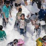 Yangon, Myanmar. Bei den Feierlichkeiten zum buddhistischen Neujahrs-Wasserfest in Myanmar, auch bekannt als Thingyan, spielen Kinder mit Seifenblasen in Bergen von Schaum. Immerhin kommen sie nicht schmutzig vom Spielen nach Hause.