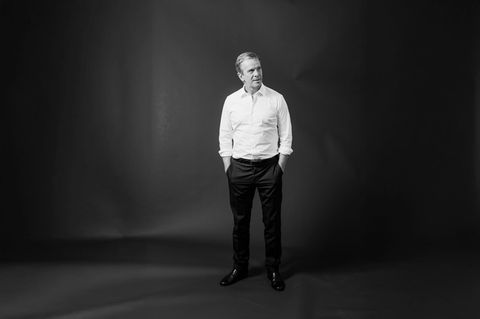 Markus Lanz steht vor einem  Fotohintergrund und schaut zur Seite