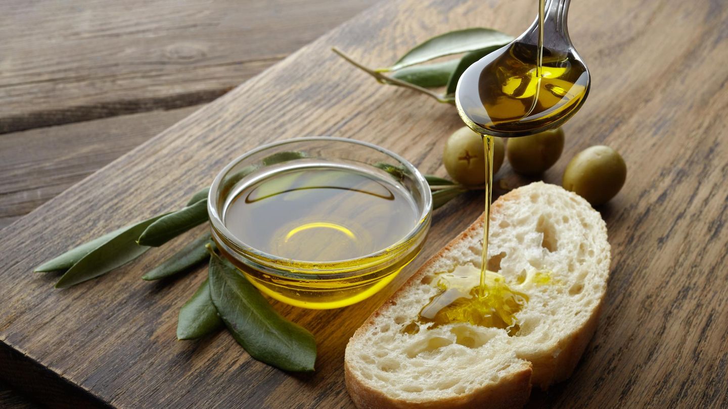 Ölivenöl tropft von einem Löffel auf ein Stück Brot