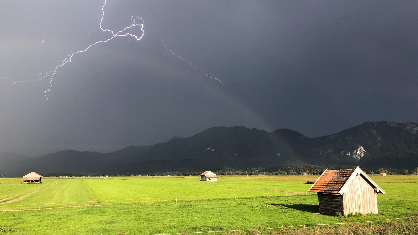 Schlehdorf, Deutschland. Der April macht – wettertechnisch zumindest – was er will. Das ist eine der bekanntesten Bauernregeln. Dieses Foto aus den bayerischen Voralpen scheint es zu bestätigen: dunkle Wolken, Sonnenschein, Blitz und Regenbogen.