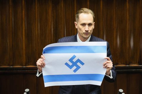 Der rechtsradikale Abgeordnete Konrad Berkowicz zeigt im Parlament von Polen eine Flagge Israels mit Hakenkreuz statt Davidstern