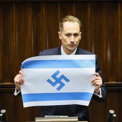Der rechtsradikale Abgeordnete Konrad Berkowicz zeigt im Parlament von Polen eine Flagge Israels mit Hakenkreuz statt Davidstern