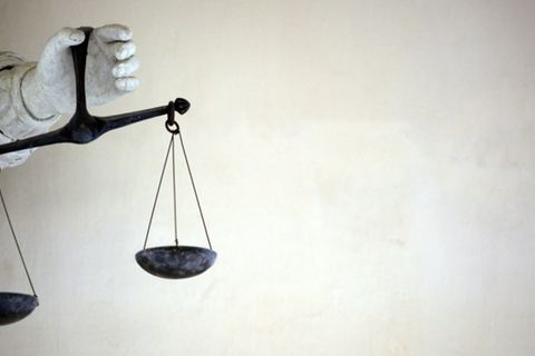 Hand einer Figur mit Waage