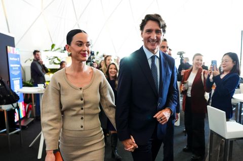 Katy Perry und Justin Trudeau lächeln in die Kamera und halten Händcheen