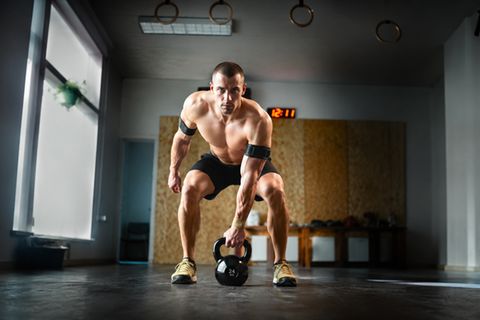Training: Ein Mann in einem Fitness-Studio trainiert mit einem Gewicht und Manschette um den Arm