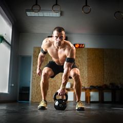 Training: Ein Mann in einem Fitness-Studio trainiert mit einem Gewicht und Manschette um den Arm