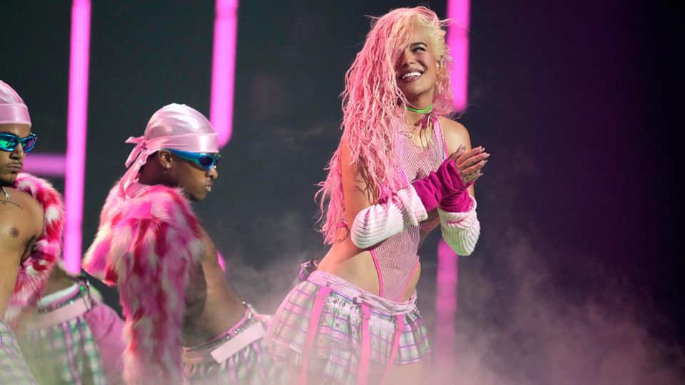 Karol G zeigt bei einem Auftritt auf der Bühne ein Lächeln