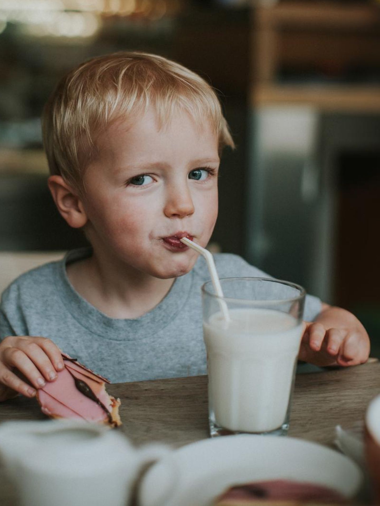 Ein Kind schlürft im Restaurant aus einem Glas Milch