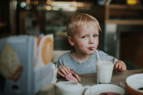 Ein Kind schlürft im Restaurant aus einem Glas Milch
